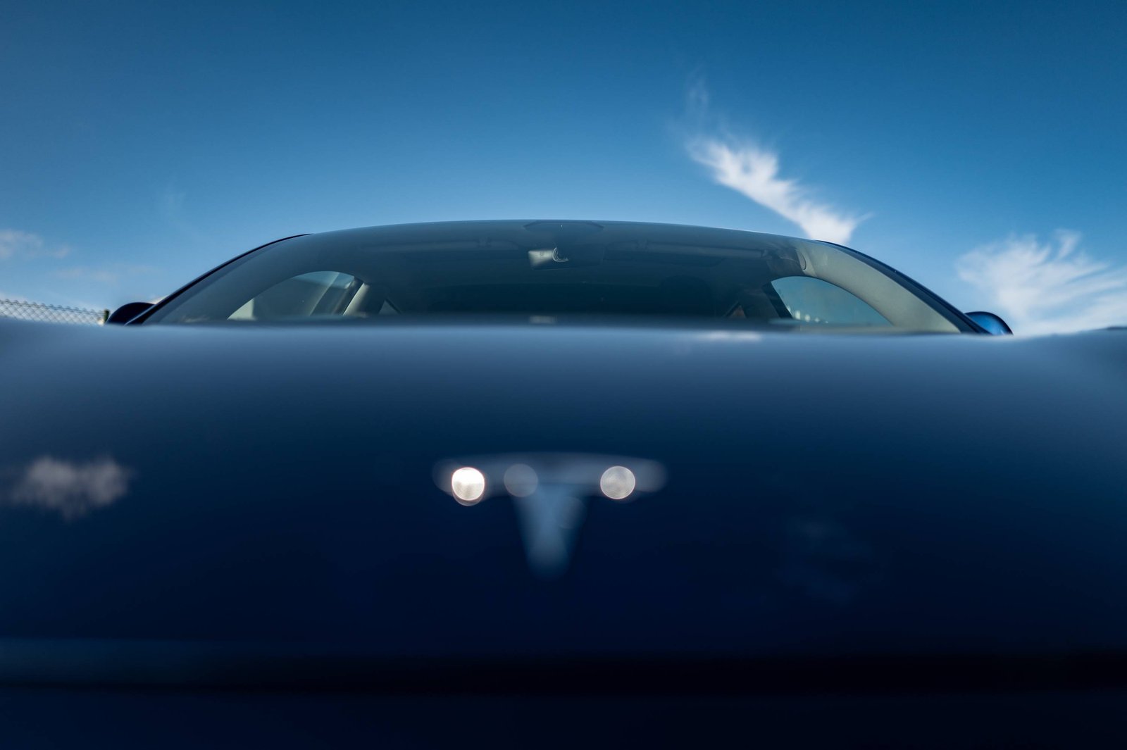 Une voiture électrique bleue reflétant le ciel.