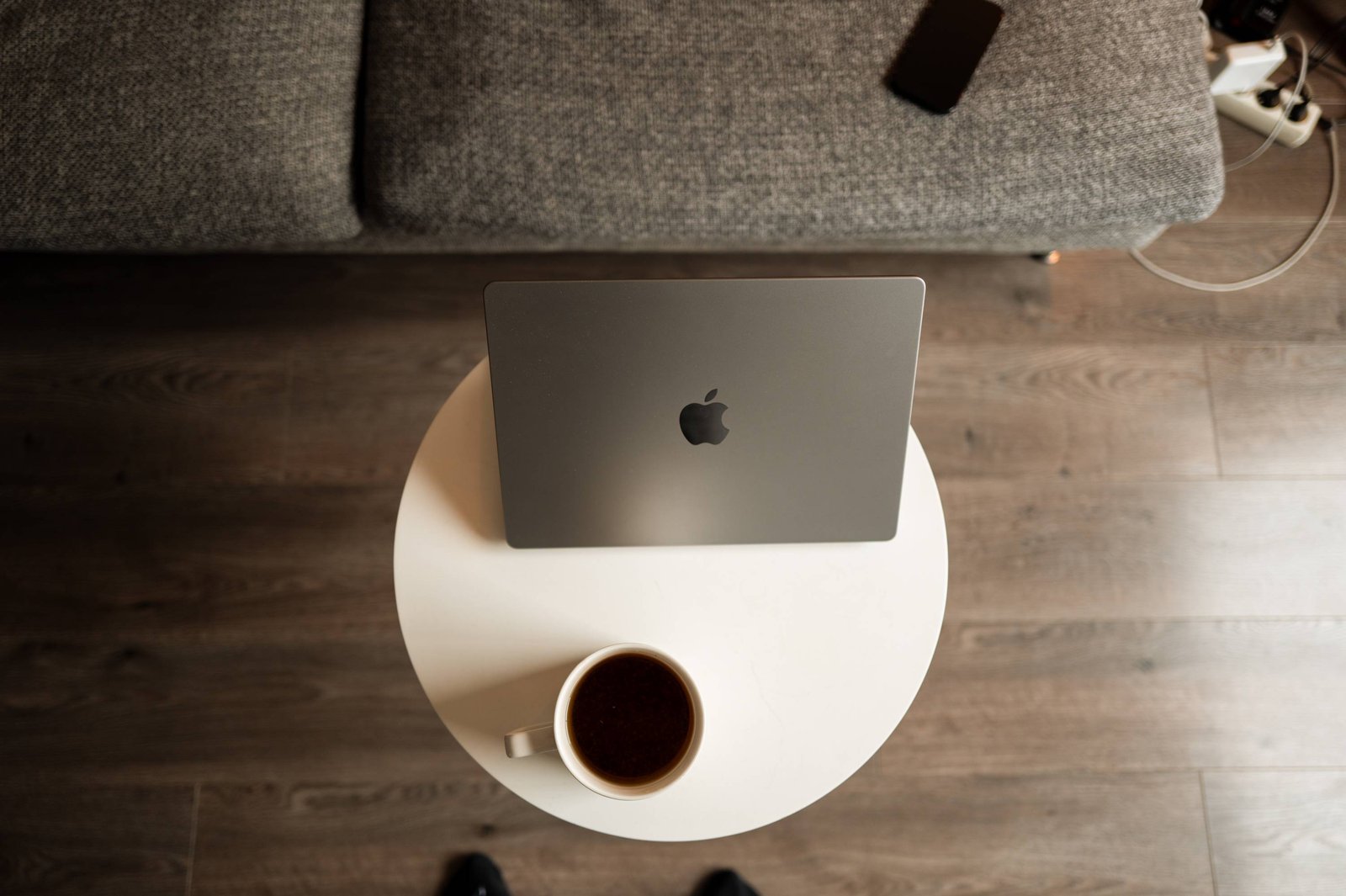 Vue en plongée d'un ordinateur portable et d'un café sur une table ronde.